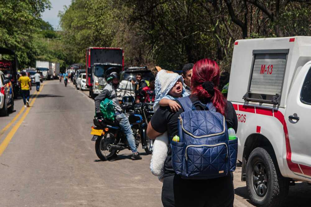 Personas caminan con bolsas y niños en brazos sorteando el bloqueo en la vía a San Juan del Cesar, a la altura de Guacoche. Foto: Jesús Ochoa.