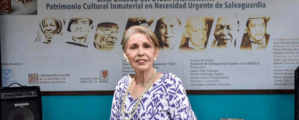Estela Durán Escalona, intérprete del vallenato tradicional y parte del equipo que elaboró el dossier técnico para la declaratoria de la Unesco, frente al afiche que conmemora los 10 años de reconocimiento mundial del género. Foto: Jesús Ochoa.
