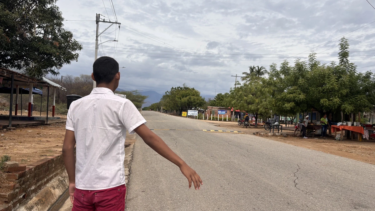 Gael Barros Arrieta, estudiante de octavo en la I.E. Patillal, extiende la mano en la vía entre La Vega Arriba y Patillal. Bajo el sol abrasador de las 1:30 p.m., espera un chance para regresar a casa tras el colegio. Foto: EL PILÓN.