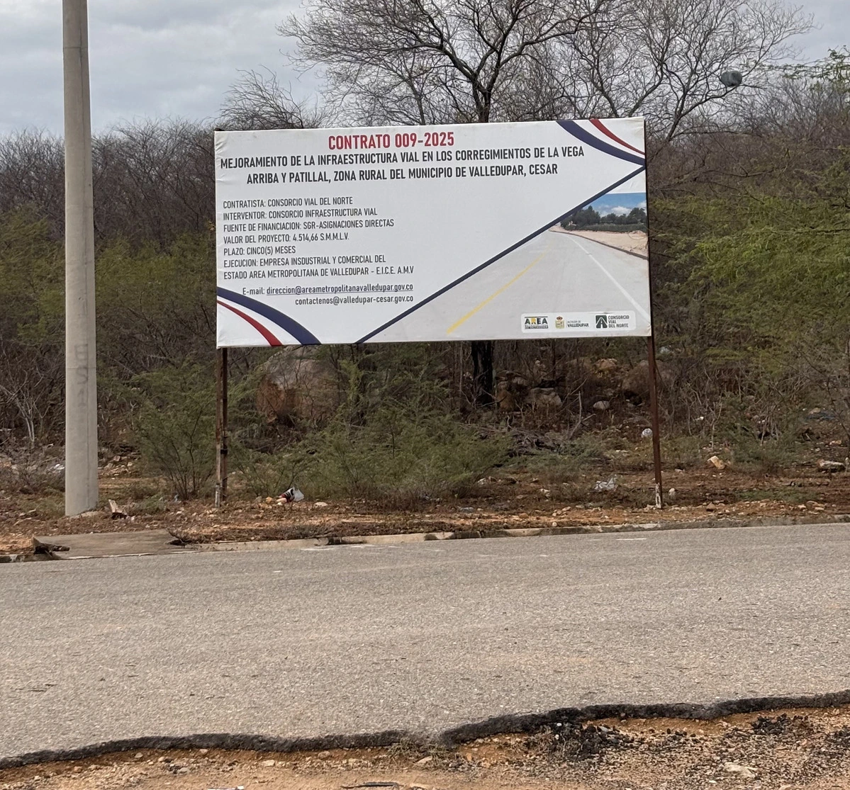 Cartel del contrato 009-2025 en la vía La Vega–Patillal con la promesa de “mejoramiento de la infraestructura vial”, frente a una obra detenida, con daños y obreros sin pago.​ Foto: EL PILÓN